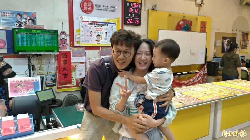 開出威力彩頭獎的店家老闆龐仲凱(左)開心地與妻小抱在一起。(記者王俊忠攝)