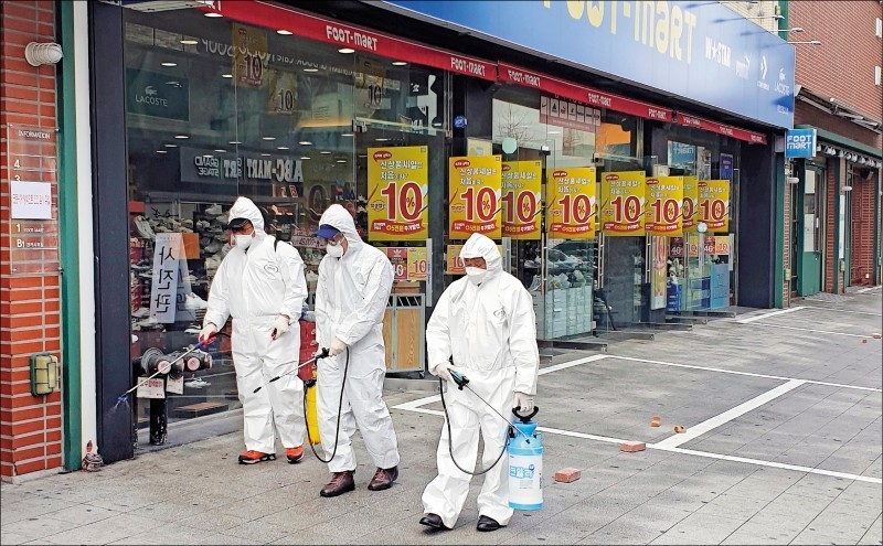 武漢肺炎疫情蔓延，韓股重挫2.48%，圖為3名清潔公司派出的人員，22日在南韓第五大城大田市的人行道上噴灑消毒劑。（路透）