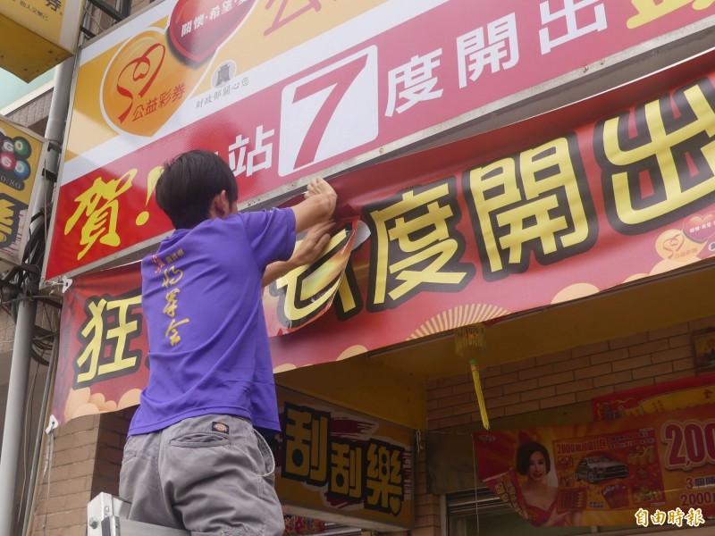 金門「一夜富」彩券行又開出頭獎，店家請人更換賀喜彩條數字。（記者吳正庭攝）
