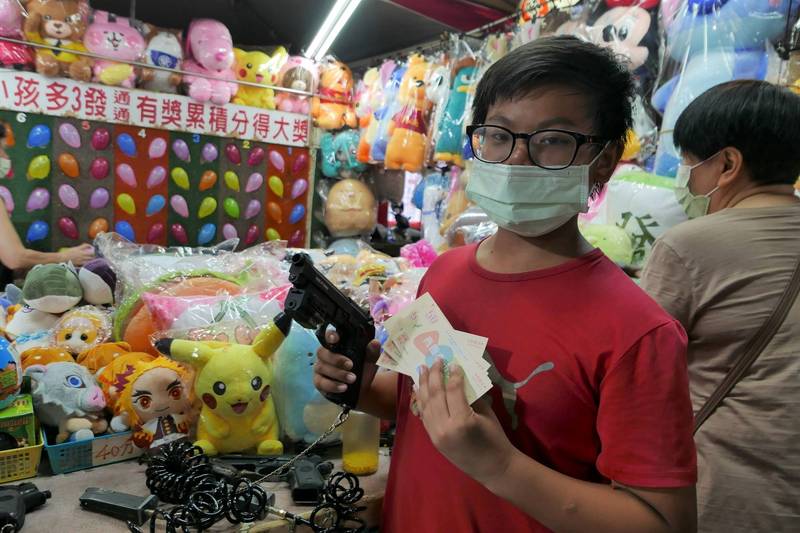 國二吳同學拿換到的夜市券玩射氣球，媽媽特別准他「想花什麼就花什麼！」。（經發局提供）