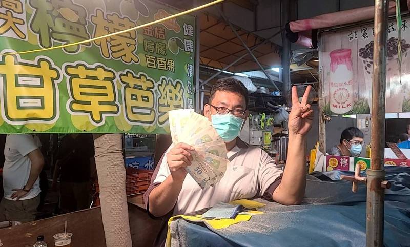 凱旋青年夜市攤商提早被掃攤，開心出示收取到的商圈夜市券。（高雄市經發局提供）