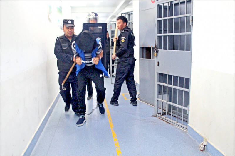 新疆警察檔案曝光,拘留營可見學員在移動過程,須戴上手銬腳鐐,甚至蒙上雙眼。(法新社)