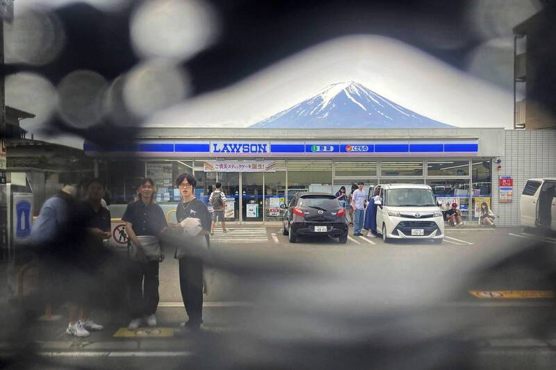 日本山梨縣富士河口湖車站的羅森超商為拍攝富士山熱門景點，因遊客諸多脫序行為使當局決定在外架起黑布遮蓋，傳出被中國遊客挖了10個洞。（美聯社）