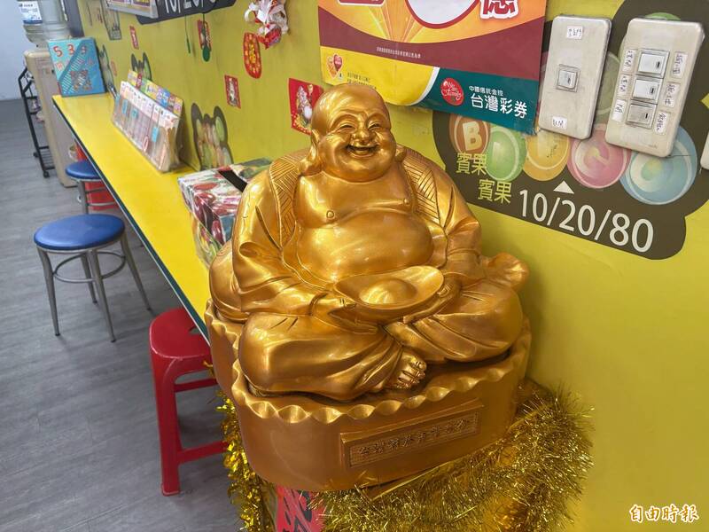 樹林區「金發野彩券行」店內有一尊招財彌勒佛，業者心血來潮將其面向門外，當天竟開出中獎。（記者陳奕劭攝）