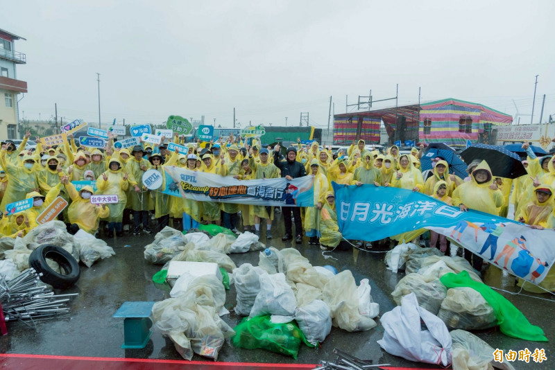 矽品精密員工今年連續第6年在中部大甲海岸線動員員工與眷屬全家一起淨灘，眾人淋雨撿拾垃圾。（記者張軒哲攝）