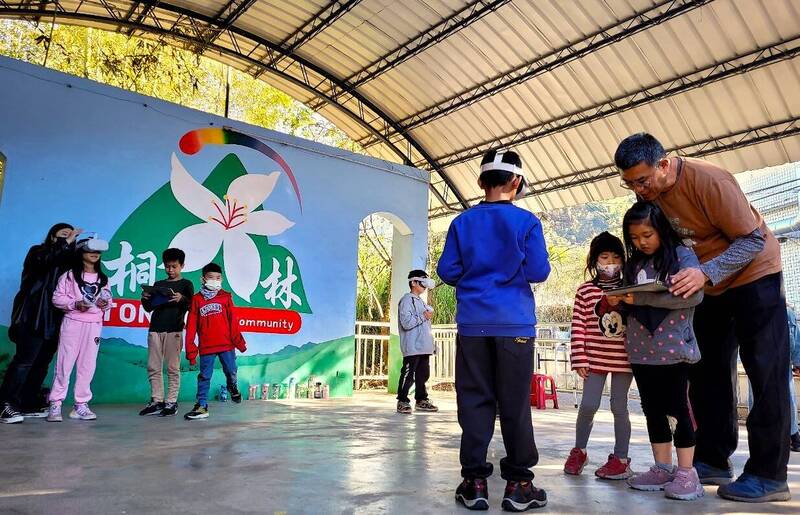 楊昌珣（右）耐心指導小朋友，結合平板與VR裝置上課。（中華電信基金會提供）