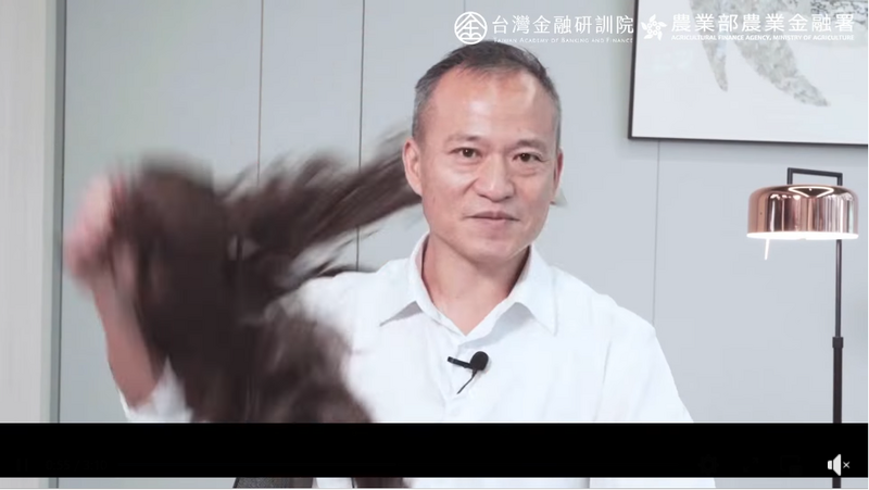 在影片中這名「女兒」還把假髮摘下，瞬間變成農金署署長李聰勇的樣貌，並指現在的詐騙集團會使用AI技術假扮成一般民眾的親友，或是電視上的名人來騙錢。（圖擷自臉書）