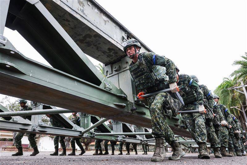 受測的工1連官兵運用抬棍搬運上、下構桁，為本次架設的MGB中框橋打好結構基礎。（青年日報提供）