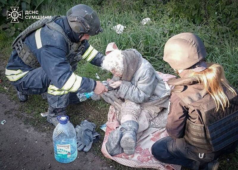 烏克蘭蘇梅地區5月8日遭俄軍空襲，一名年長婦女受傷獲救，搜救人員正為她提供飲水與照護。（美聯社）