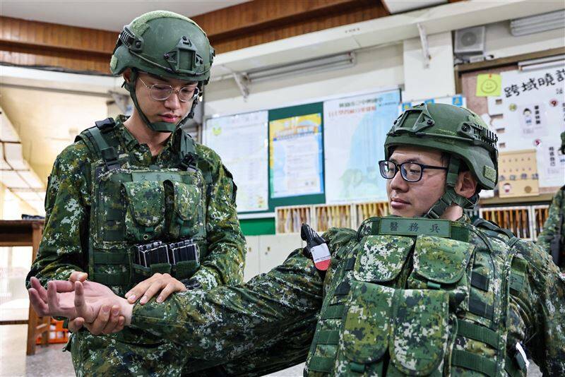 陸軍步兵206旅步1營戰支連召員以手指評估傷員脈搏，確認包紮後血流情形是否減緩。（取自青年日報）