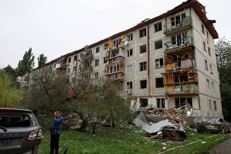 。居民站在基輔汽車和一棟公寓大樓旁。（路透）