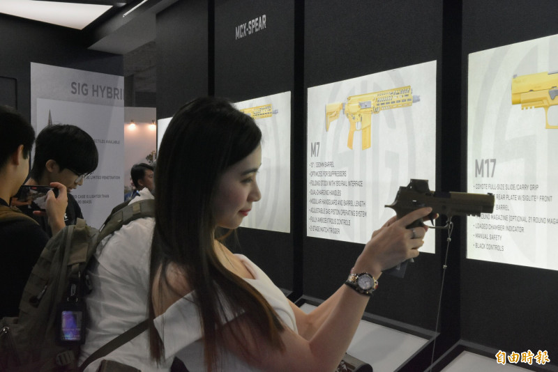 國防展各家國防廠商雲集，展場Show girl同樣大放異彩，手持槍械。（記者吳哲宇攝）
