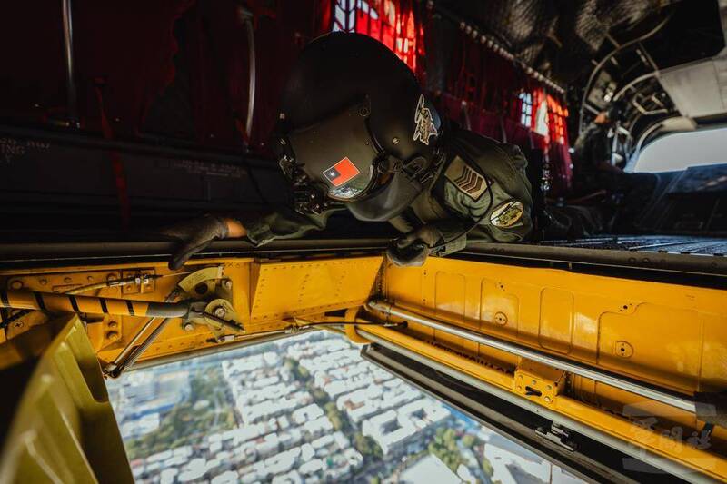 這張照片更是特別，CH-47直升機上的中央吊掛手，俯身到吊掛口，全程目視國旗與配重塊，確保任務順利完成。（圖：軍聞社提供）