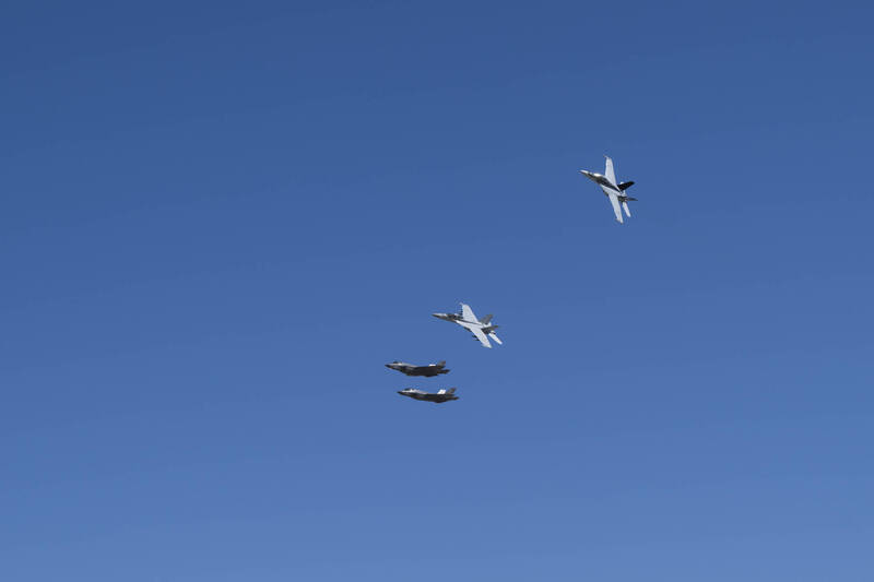 赫格塞斯坐上超級大黃蜂戰機（右上左滾者）體驗同乘飛行。（美軍DVIDS網站）