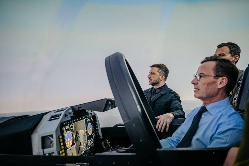圖為瑞典總理克里斯特森（駕駛艙內者）、烏克蘭總統澤倫斯基（駕駛艙外者），一同體驗JAS 39E/F戰機飛行模擬器的情形。（瑞典總理克里斯特森X帳號）