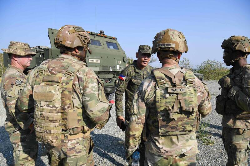 美軍士兵與菲律賓官兵於16日在菲律賓麥格塞塞堡（Fort Magsaysay）進行「海馬士」（HIMARS）機動火箭系統實彈演練前進行戰術溝通。此次「肩並肩」軍演中，美菲日等國將針對防空、反艦及多管火箭打擊進行深度整合，展現針對特定區域威脅的聯合防衛能力。（法新社）