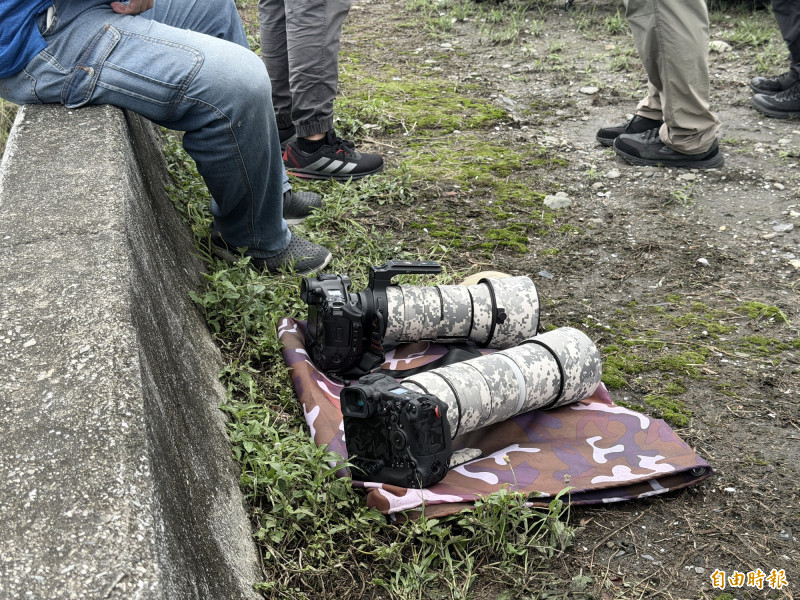 太陽曬到「大砲」發燙，軍事迷先將沈重的器材置地等待。（記者劉人瑋攝）