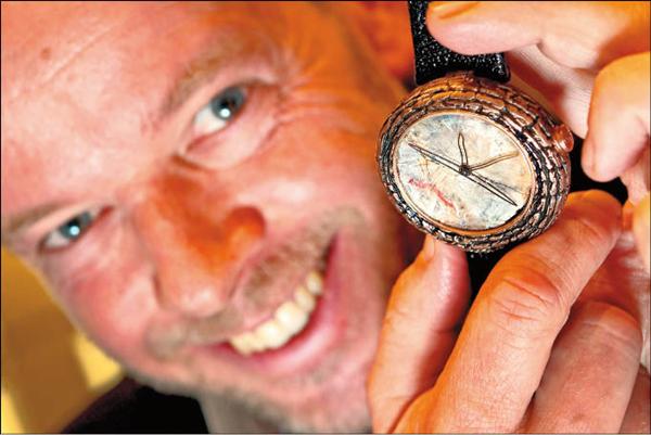 瑞士鐘錶設計師Yvan Arpa拿著以恐龍糞便化石打造面盤的奇特腕錶。（法新）