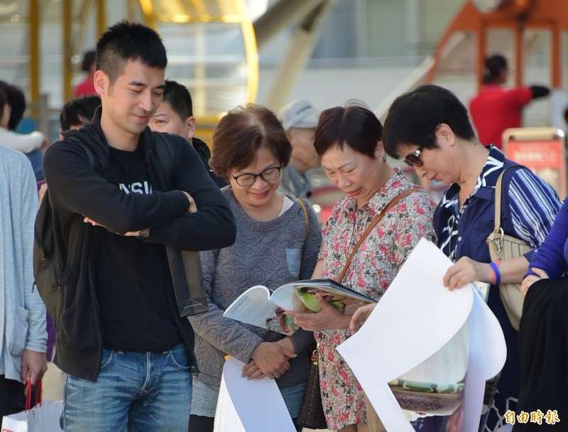 簡宏霖寫真集簽書會，簡宏霖哥哥（左）、媽媽和阿姨在路旁仔細研究寫真集。（記者胡舜翔攝）