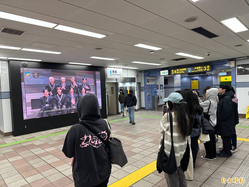 粉絲圍在捷運欣賞台北專屬歡迎影片。（記者許世穎攝）