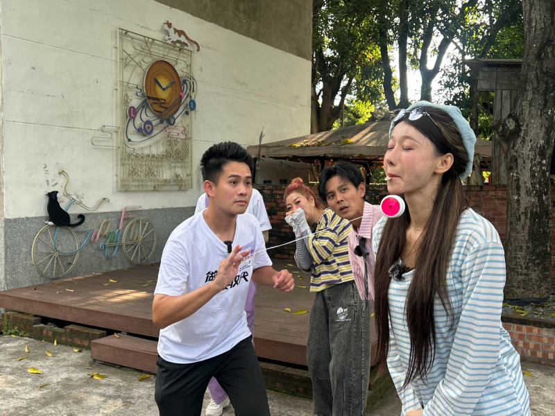 楊元慶（右）用溜溜球打掉李雅英含著的硬幣。（民視提供）