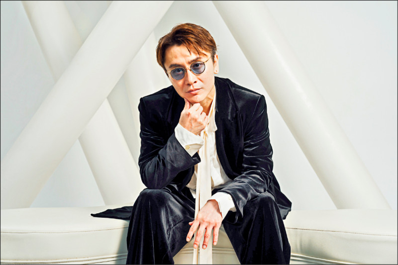 色付き眼鏡をかけ、黒いスーツ姿で椅子に腰掛ける安田章大