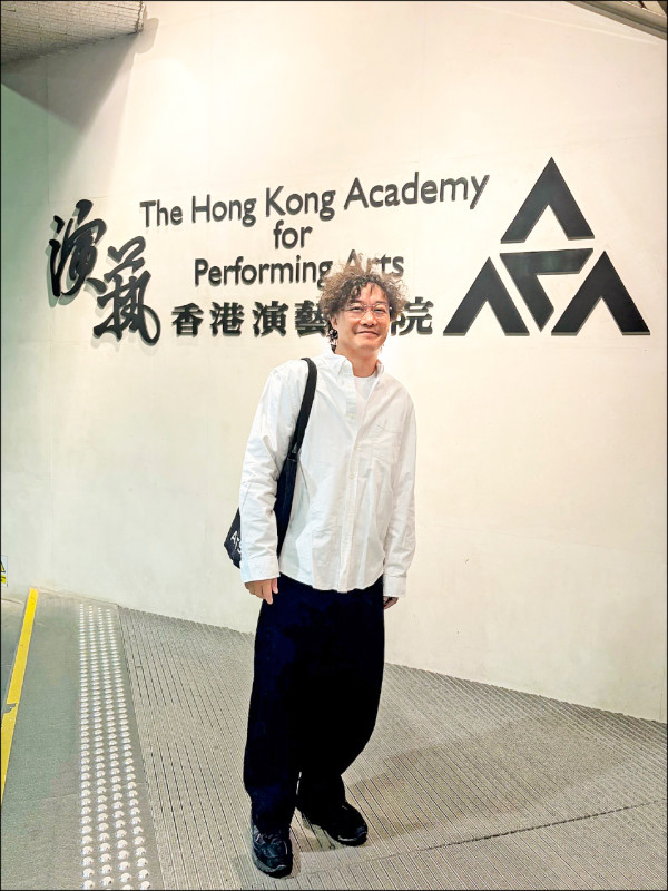 香港演藝學院の壁面の前に立つ陳奕迅