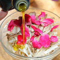 菇上鋪上玫瑰花瓣，並撒上鹽、白胡椒粉調味，再淋上橄欖油。