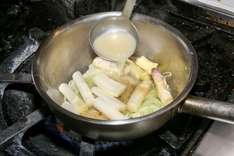 洋蔥絲、青蒜苗絲、西洋芹絲用少許橄欖油炒至軟化，再加入富士蘋果、切成小段的白蘆筍與雞高湯，用小火煮20分鐘。
