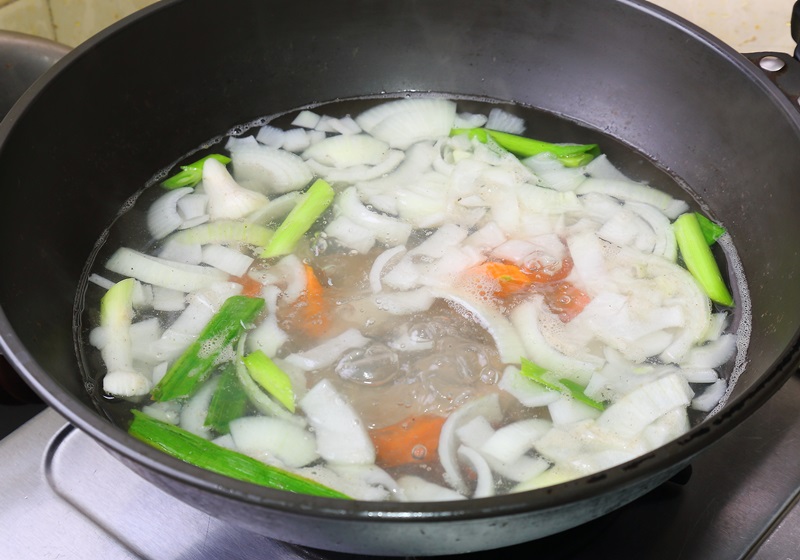 製作高湯，將胡蘿蔔、洋蔥切小塊，西洋芹、蒜苗切段，起一鍋熱水，放入以上食材和豬骨，待煮滾後，再以小火煮40分鐘。