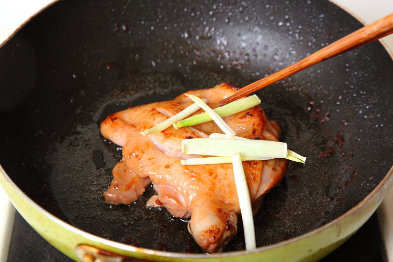 約3分鐘後轉小火，讓雞腿肉慢慢煎熟外，小火能保存住肉汁，接著放入少許蔥段提味。
