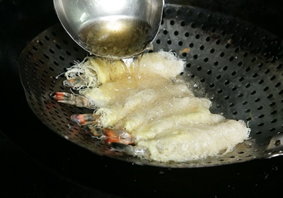 鍋裡倒入沙拉油，大火熱鍋至150∼180℃後，再轉小火，先將蝦子放於漏杓，澆淋上熱油先塑型，避免下鍋後彼此沾黏。