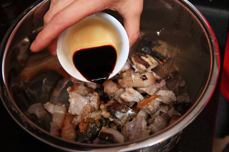 取一新鍋，放入煎好的鹹魚、五花肉及醬油、適量開水。