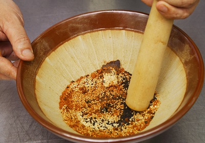 取一圓缽，倒入白芝麻10克、黑芝麻5克、紫蘇籽5克、乾紫菜5克、乾橘子皮15克、辣椒粉15克、花辣粉15克，以擂棒完全磨碎，即為七味辣椒粉，撒於美乃滋上，即為鮭魚串之蘸醬。