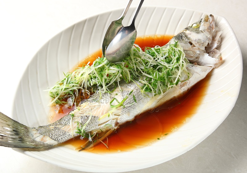 先將魚身上方的辛香料、蔥蒜等擺盤放到盤子側邊，並將魚鰭拿掉。