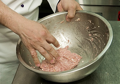 將三層肉絞肉放入碗中，加入鹽、糖拌勻，將絞肉拿起，在碗中輕輕拋打，打到肉出現黏稠狀態即可。