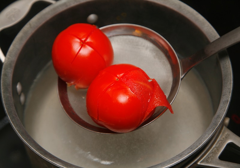 番茄洗淨後在非蒂頭端劃十字刀,準備一鍋清水,水煮滾後丟入番茄,汆燙後撈起,剝除外皮。