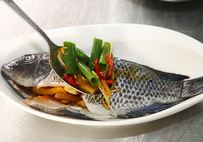 調味醬用湯匙舀取，塞入吳郭魚的肚中，剩餘的調味醬直接淋在魚上。