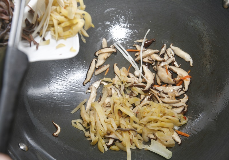 大火起油鍋，先放入香菇、榨菜炒香。