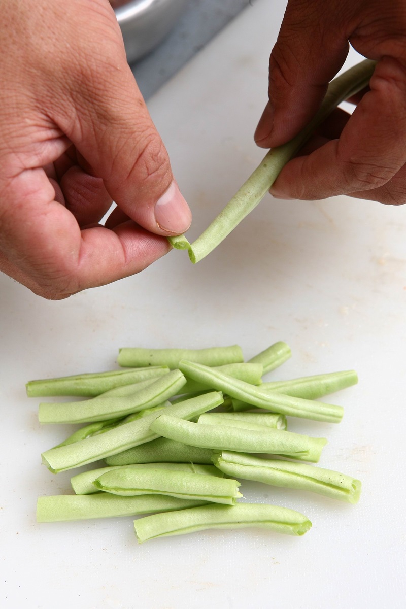 將四季豆豆莢接縫處的纖維一條條挑出，每根視其長短，分別折成3∼4段。