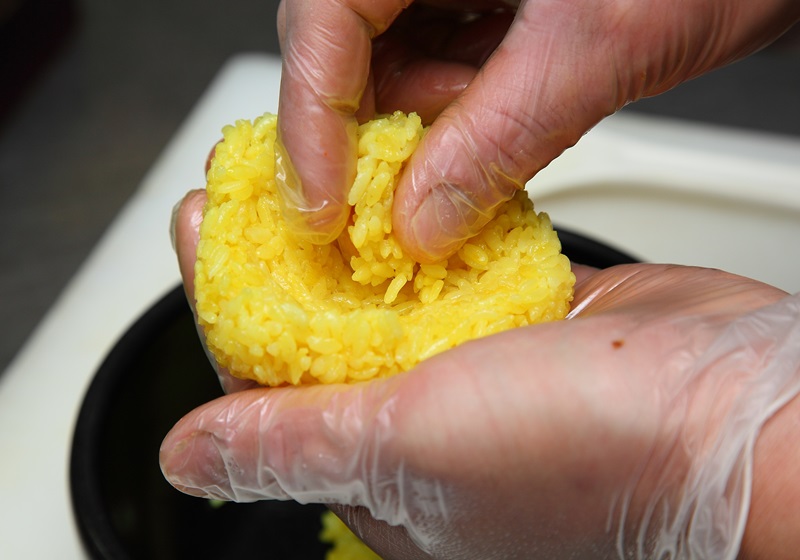 將鬱金香飯放在左手掌上順時針旋轉，並從中間開始往上加飯，會比從兩側加飯更容易捏出三角形飯糰。此外，擺盤時可加入紫蘇葉、日本乾辣椒絲、蔥白細絲當做裝飾。