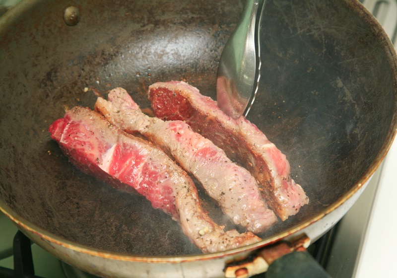 大火熱油鍋，油熱冒煙後放入牛小排，翻轉使每一面均勻上色後熄火，此時牛小排約三分熟，再蓋上蓋子燜至五分熟。