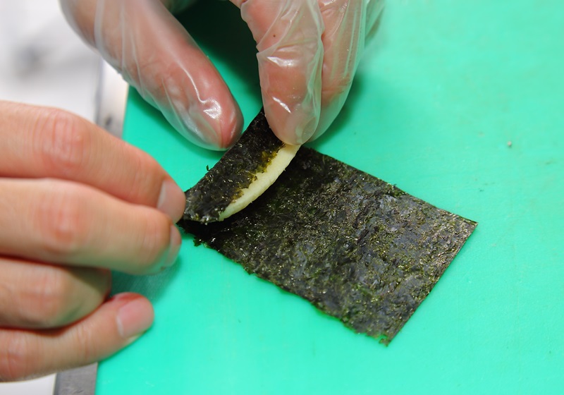 將鯛魚片加入少許胡椒鹽抓勻調味，取魚肉鋪平，放上包捲好的海苔香蕉條，再用魚片包捲起來。