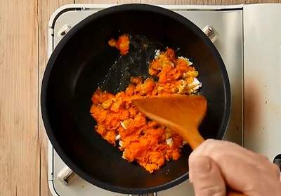 【製作偽蟹黃】利用湯匙把紅蘿蔔刮成泥。熱鍋下油、鹹蛋黃和紅蘿蔔泥爆香，炒勻到起泡後下適量的水拌勻，盛起備用。