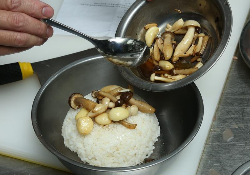 把鍋中的菇類、茶油和蒜仁加入白飯中，加入鹽、糖拌勻後，於盤中鋪平，再將肉平鋪白飯上，包上耐熱保鮮膜，入蒸籠或電鍋中加熱5～10分鐘即可取出。