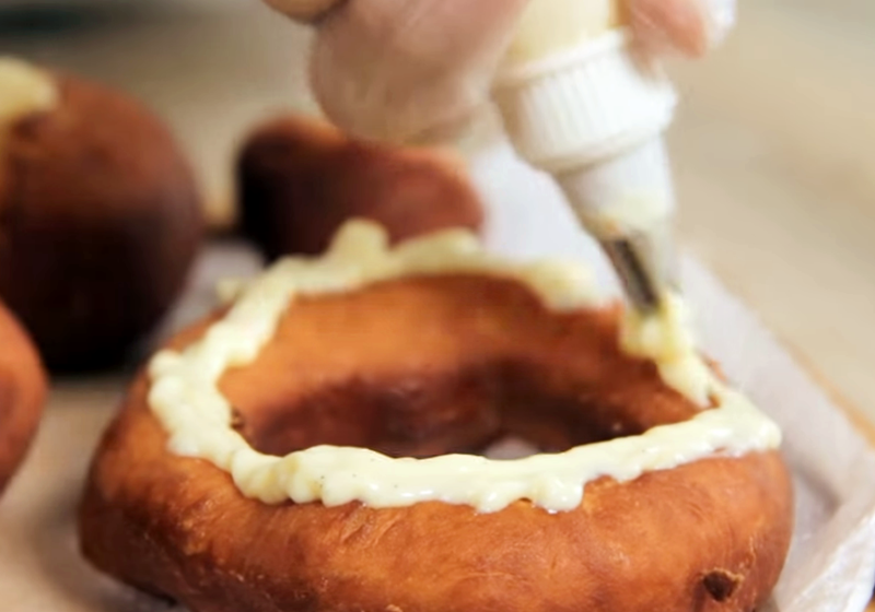 將卡士達醬擠入甜甜圈中，表面也可擠上醬料作為裝飾，灑上糖粉即完成。