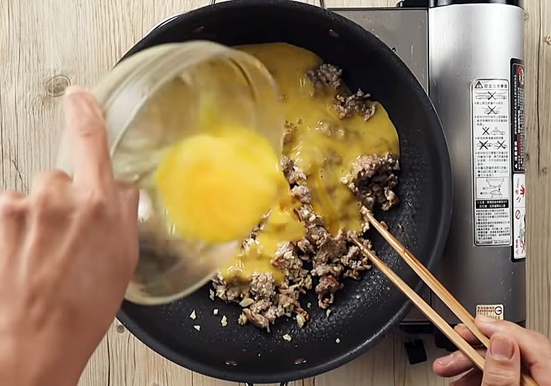 倒入打散的蛋液，煎至蛋皮凝固可滑動後，淋上一圈花椒油，翻面續煎。