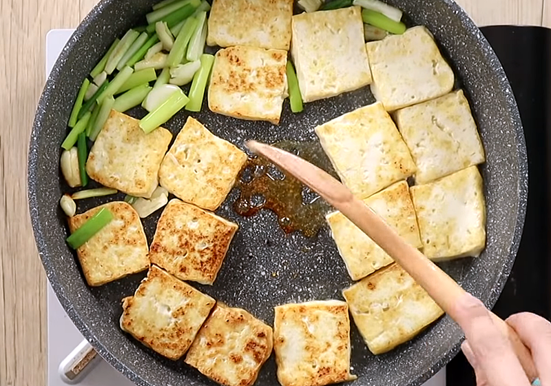 板豆腐煎至雙面上色後，推至鍋緣，騰出中央空間，下糖炒至稍微焦糖化上色。