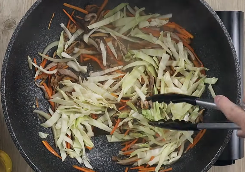 下香菇水、醬油、少許水、高麗菜，炒勻後下白胡椒、鹽、糖拌炒至微微收汁。