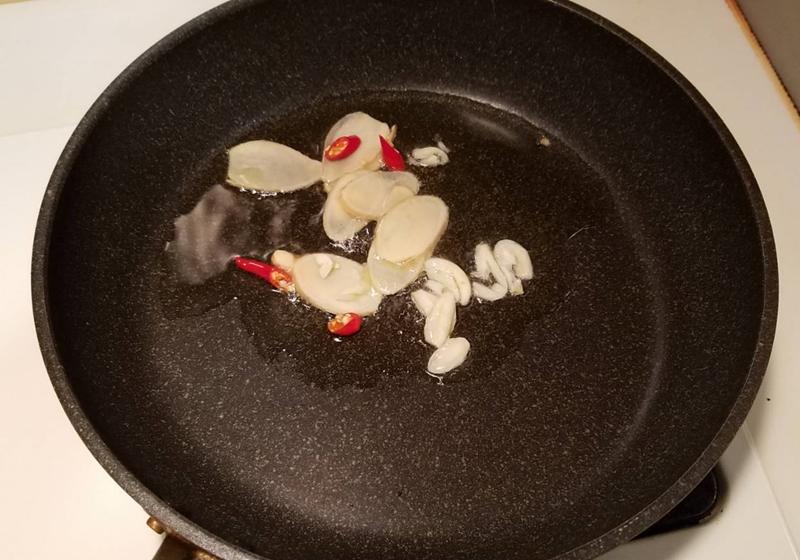 豬肉片用醃料抓醃片刻。取鍋下適量油，煸香辣椒、蒜片、薑片。